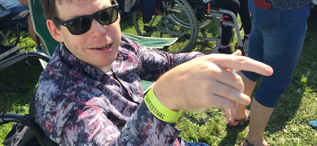 Mand der sidder i kørestol, sidder og smiler med solbriller på til Skive Festival 2021