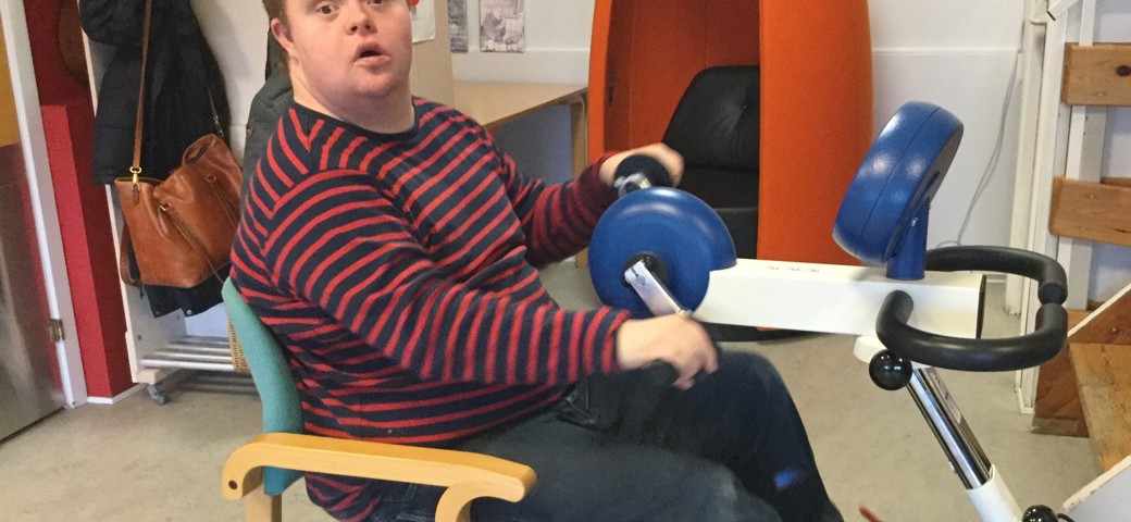 Person sidder ned og træner armene med en armcykel